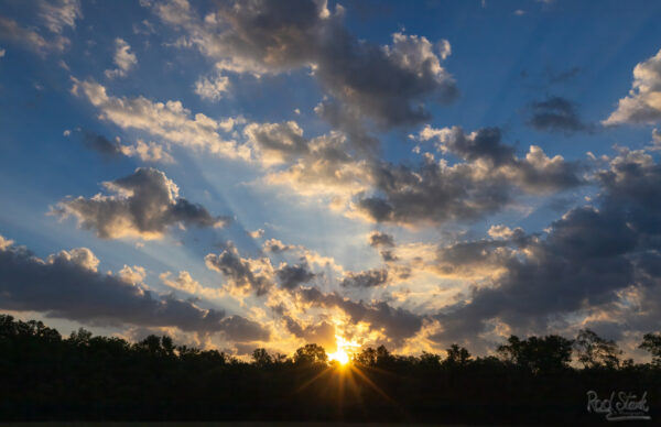 Sunrise with sun rays and cloudy sky