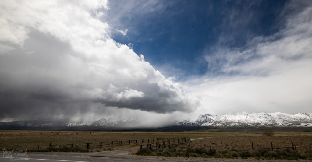 Snowstorm front on the plains with snow covered mountains in the background