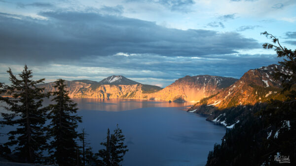 Crater lake sunset with the mountains illuminated in yellow sunshine