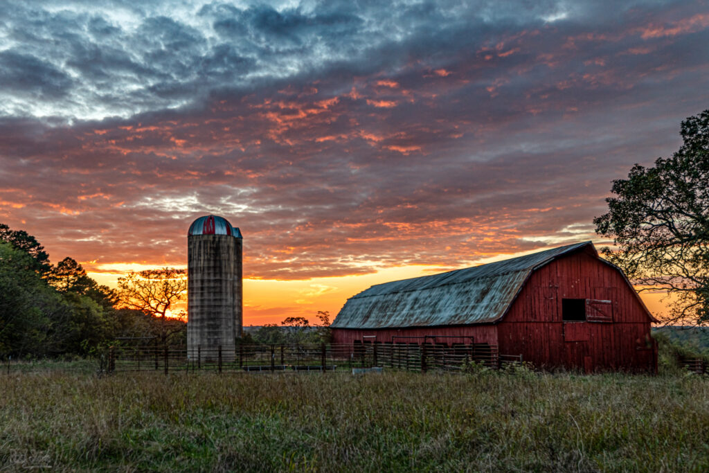 Old barn with silo and a beautiful sunset behind