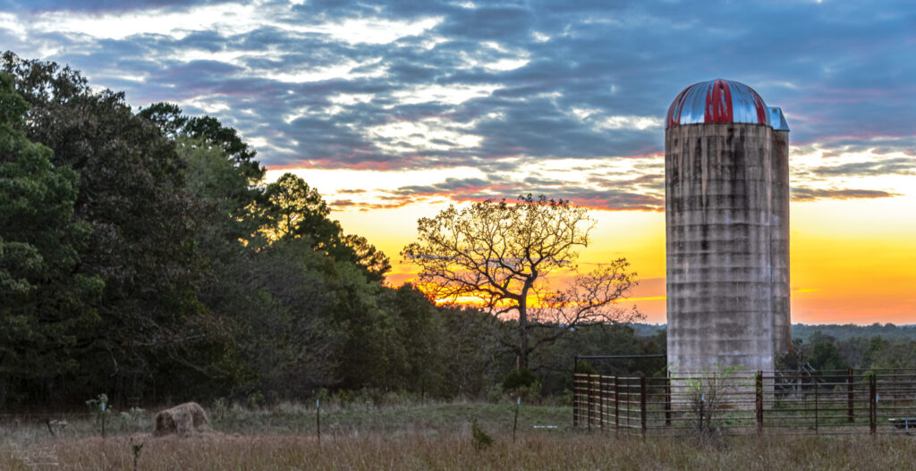 Sunset with a farm silo in yellow, pink and blue hues